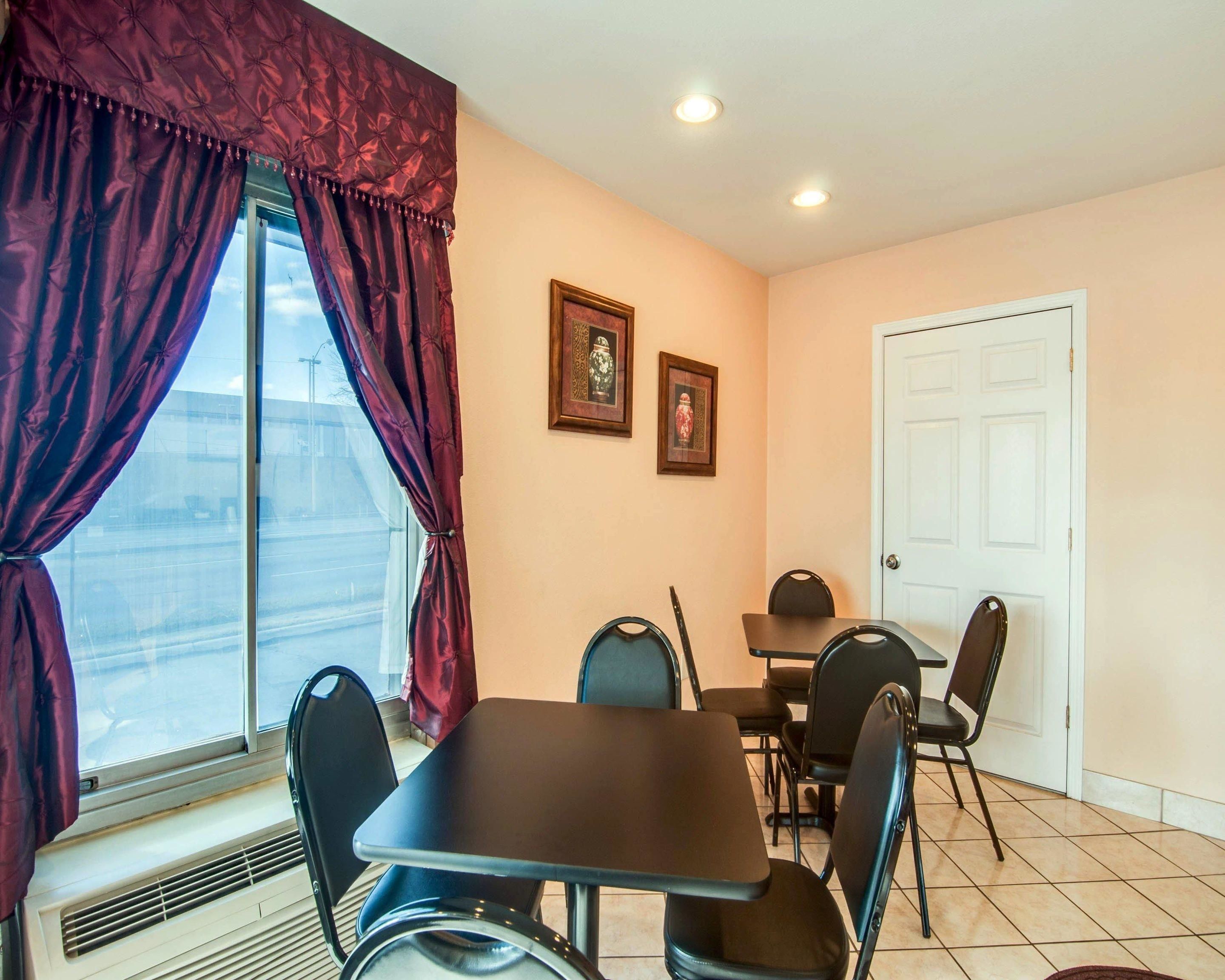 A dining area with a table and chairs, a window with curtains, and two framed pictures on the wall.