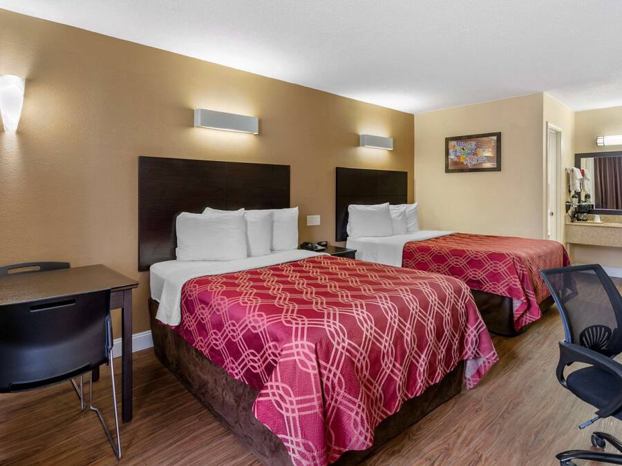 A hotel room with two beds, a desk, and a chair.