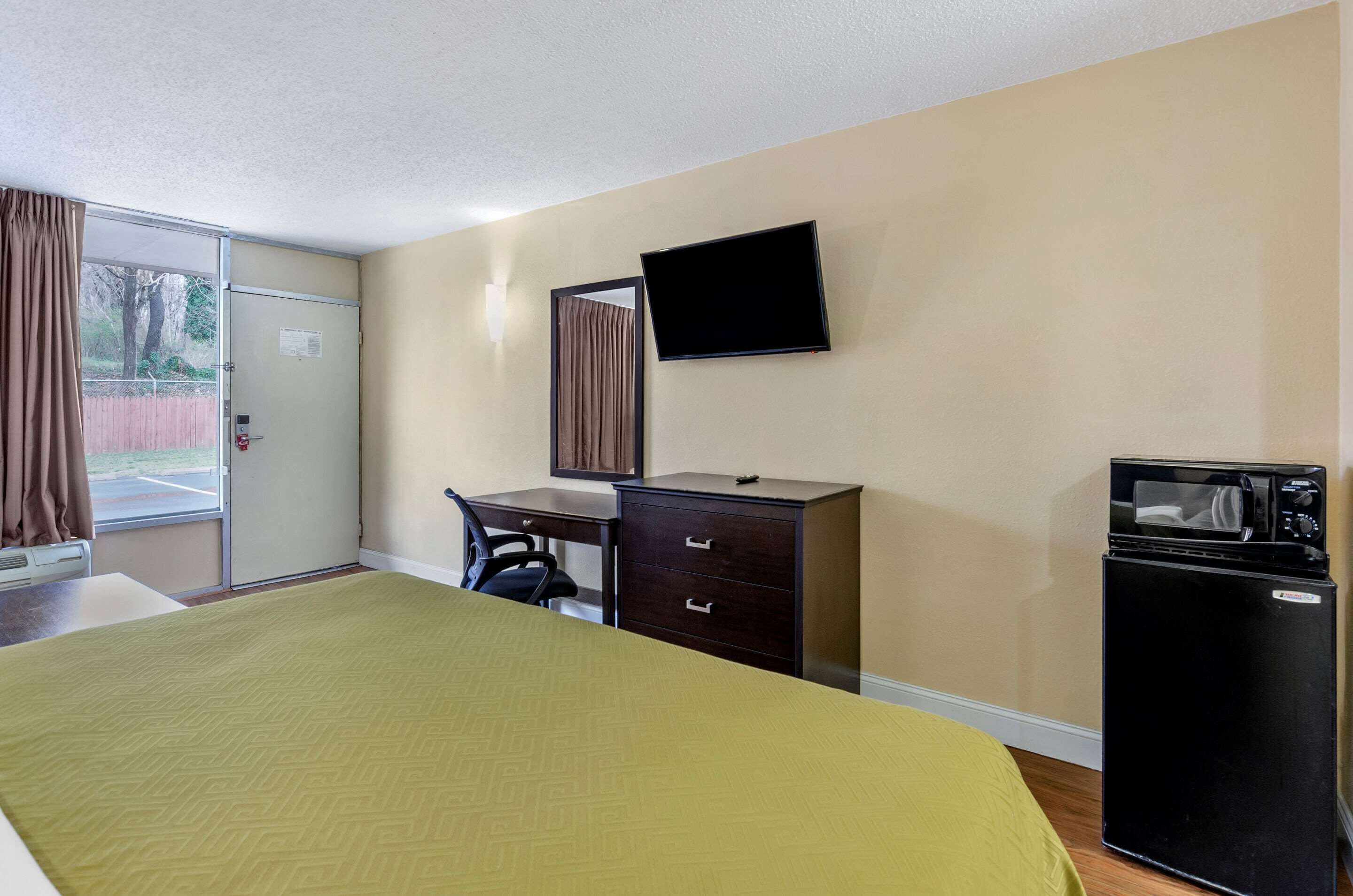 Une chambre d’hôtel équipée d’un lit, d’un bureau, d’une chaise, d’une télévision, d’un four à micro-ondes et d’un réfrigérateur.