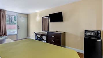 Une chambre d’hôtel équipée d’un lit, d’un bureau, d’une chaise, d’une télévision, d’un four à micro-ondes et d’un réfrigérateur.