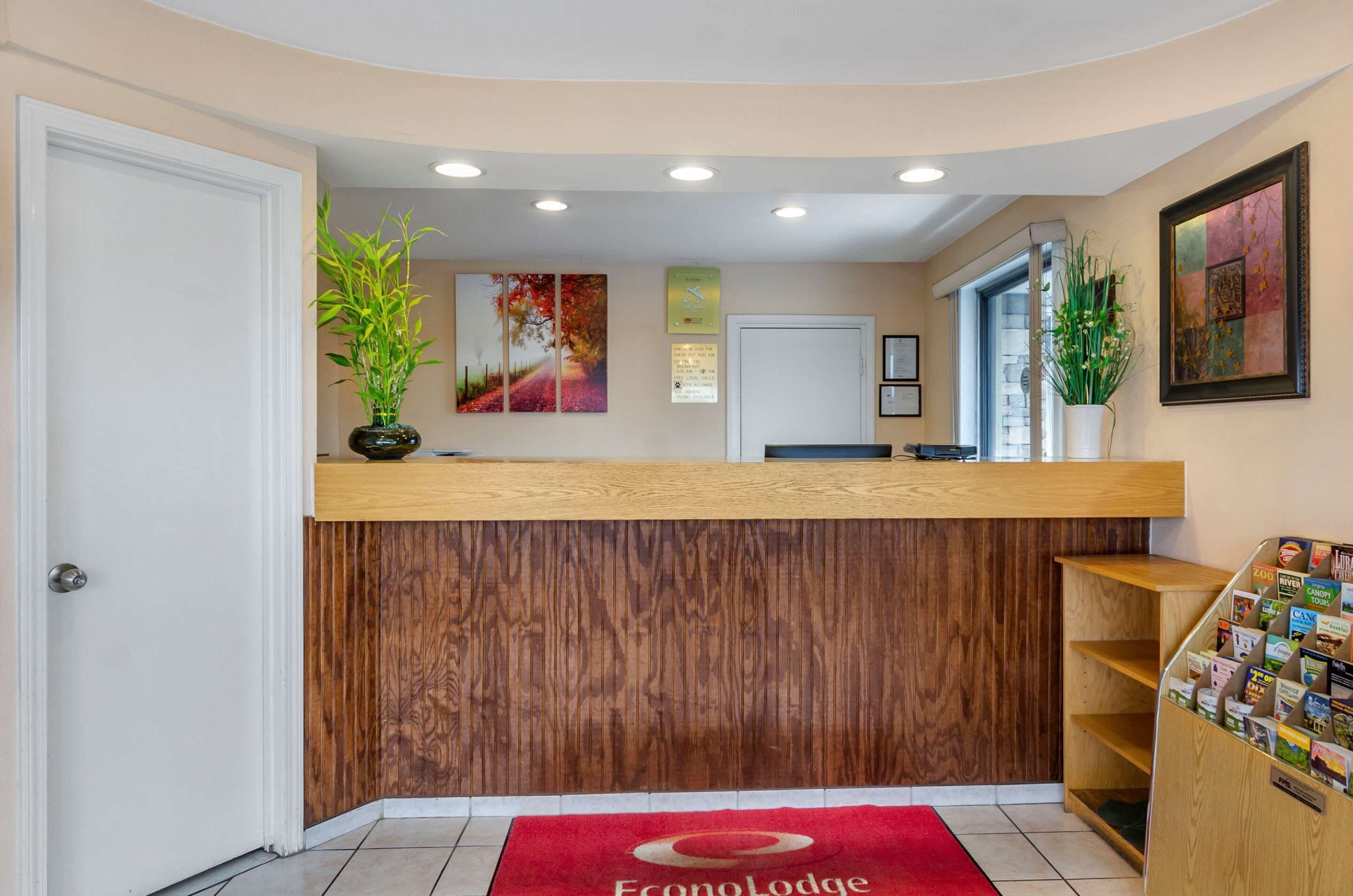 A reception area with a wooden counter, a red carpet, and a wall with framed pictures.