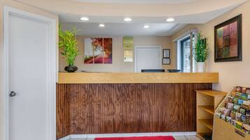 A reception area with a wooden counter, a red carpet, and a wall with framed pictures.