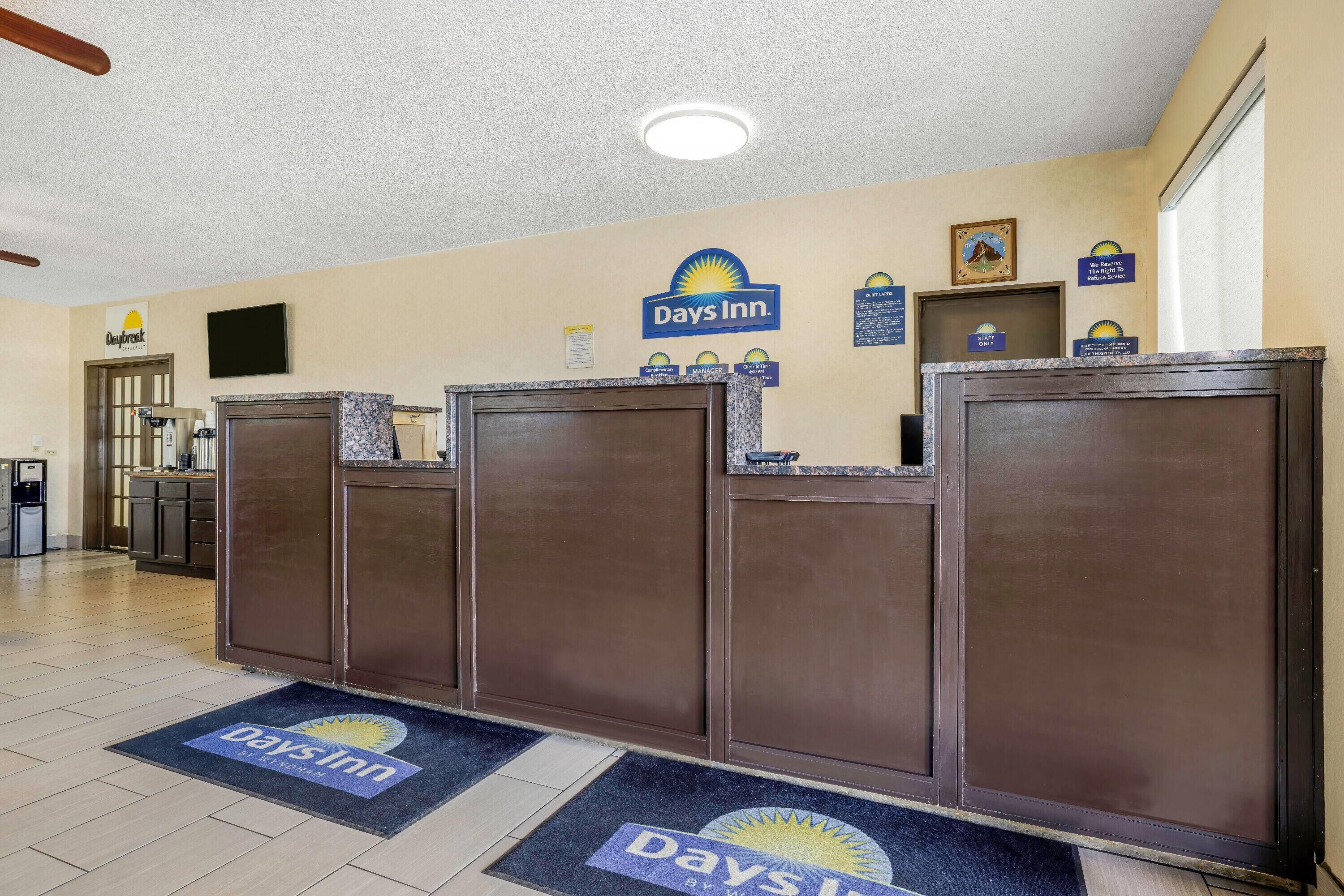Un espace d’accueil avec une enseigne Days Inn, un comptoir de réception, une machine à café et un téléviseur fixé au mur.