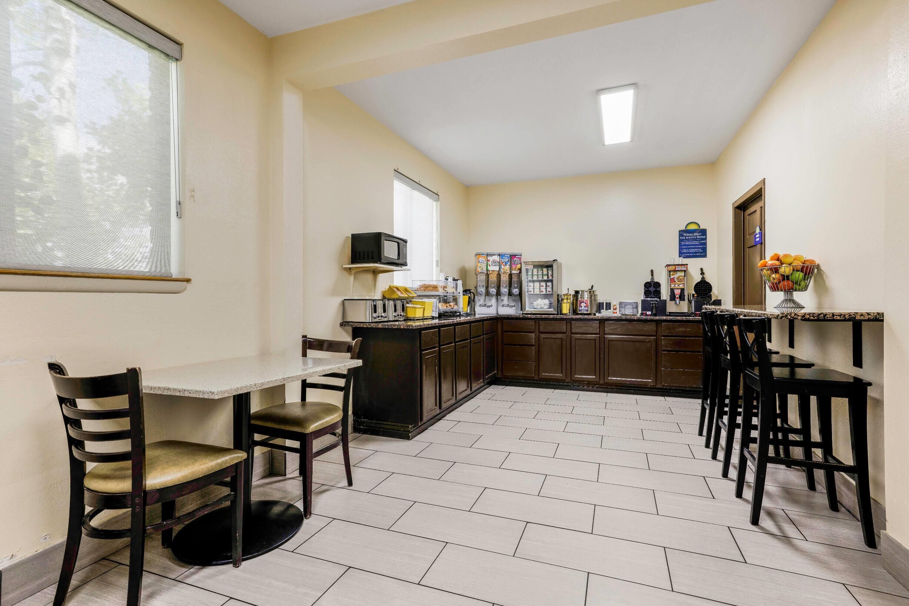 A compact kitchen with a dining area, featuring a microwave, refrigerator, and a small coffee station.