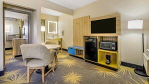 Ein Hotelzimmer mit Essbereich, Mikrowelle, Kaffeemaschine und Fernseher.