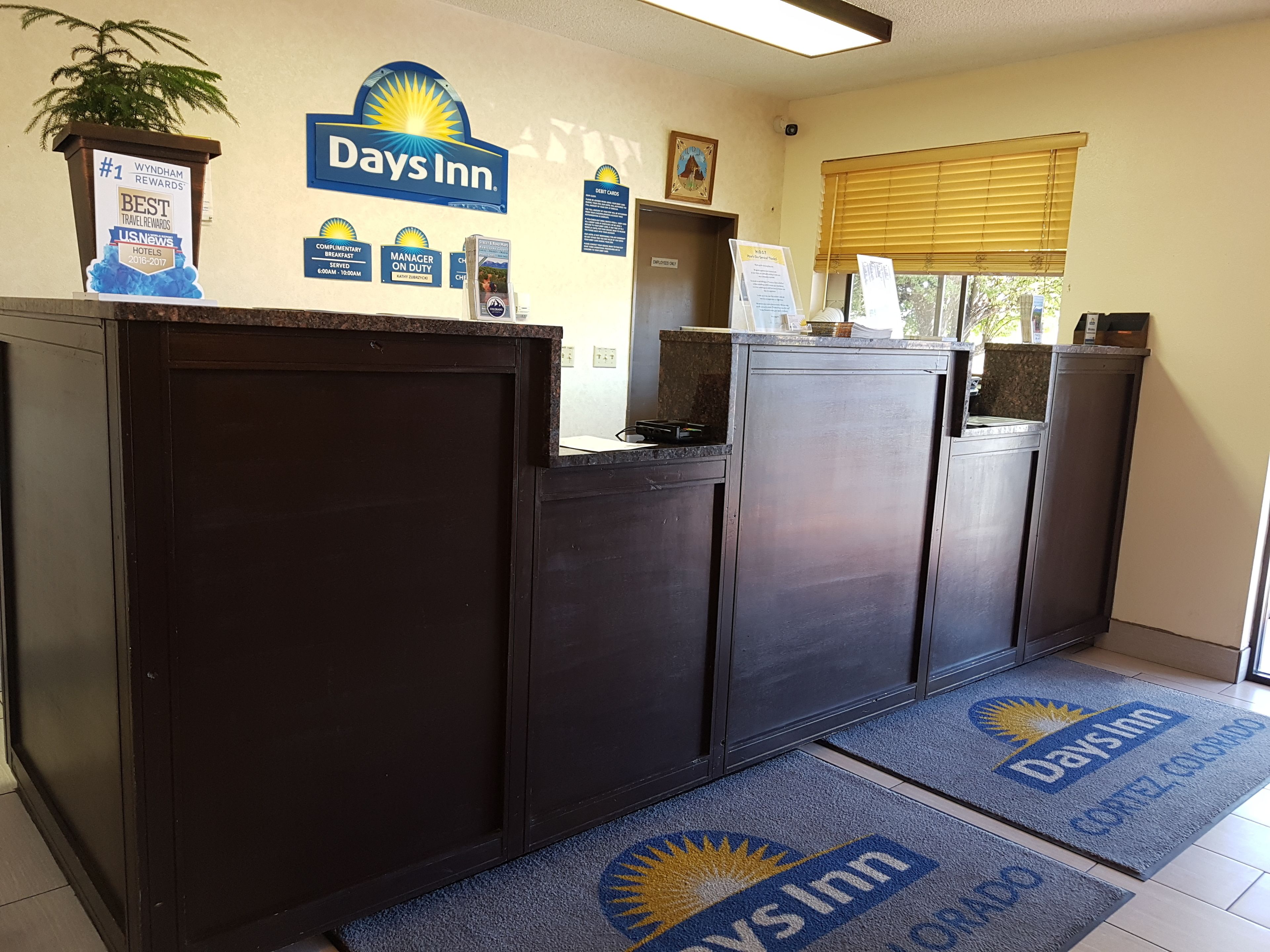 Un'area reception con il cartello Days Inn, un segnale che indica il responsabile di turno e un cartello con i loghi delle carte di credito.