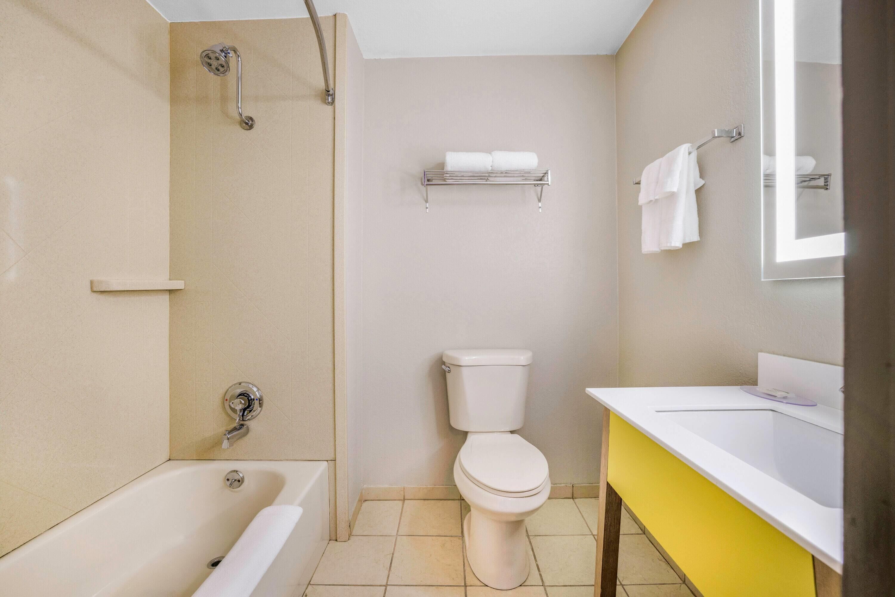 A bathroom with a bathtub, toilet, and a sink with a mirror.