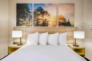 A hotel room with a large bed, two bedside tables with lamps, and a wall-mounted artwork depicting a forest scene. - Days Inn by Wyndham Cortez (Cortez)