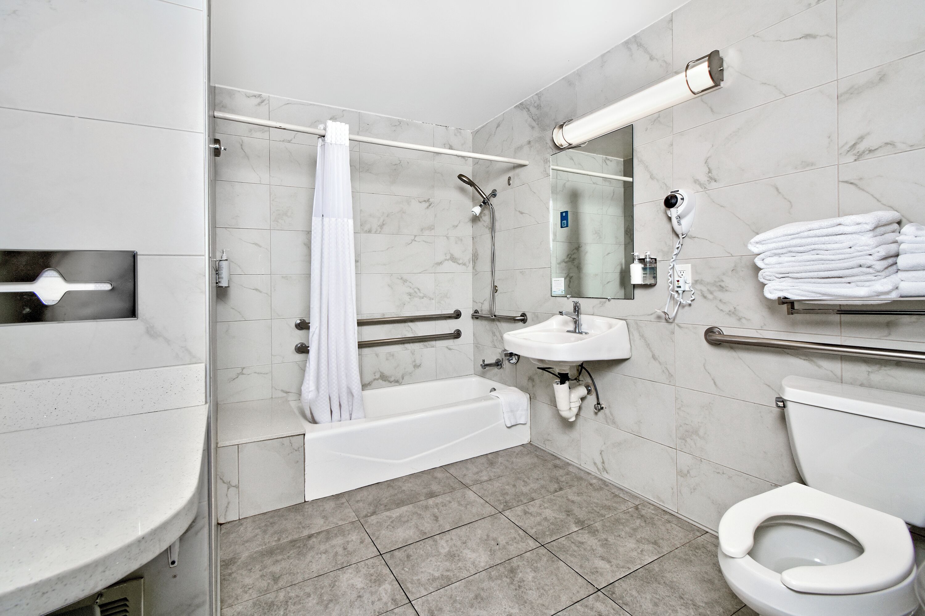Et moderne badeværelse med badekar, toilet, vask og brusebad.