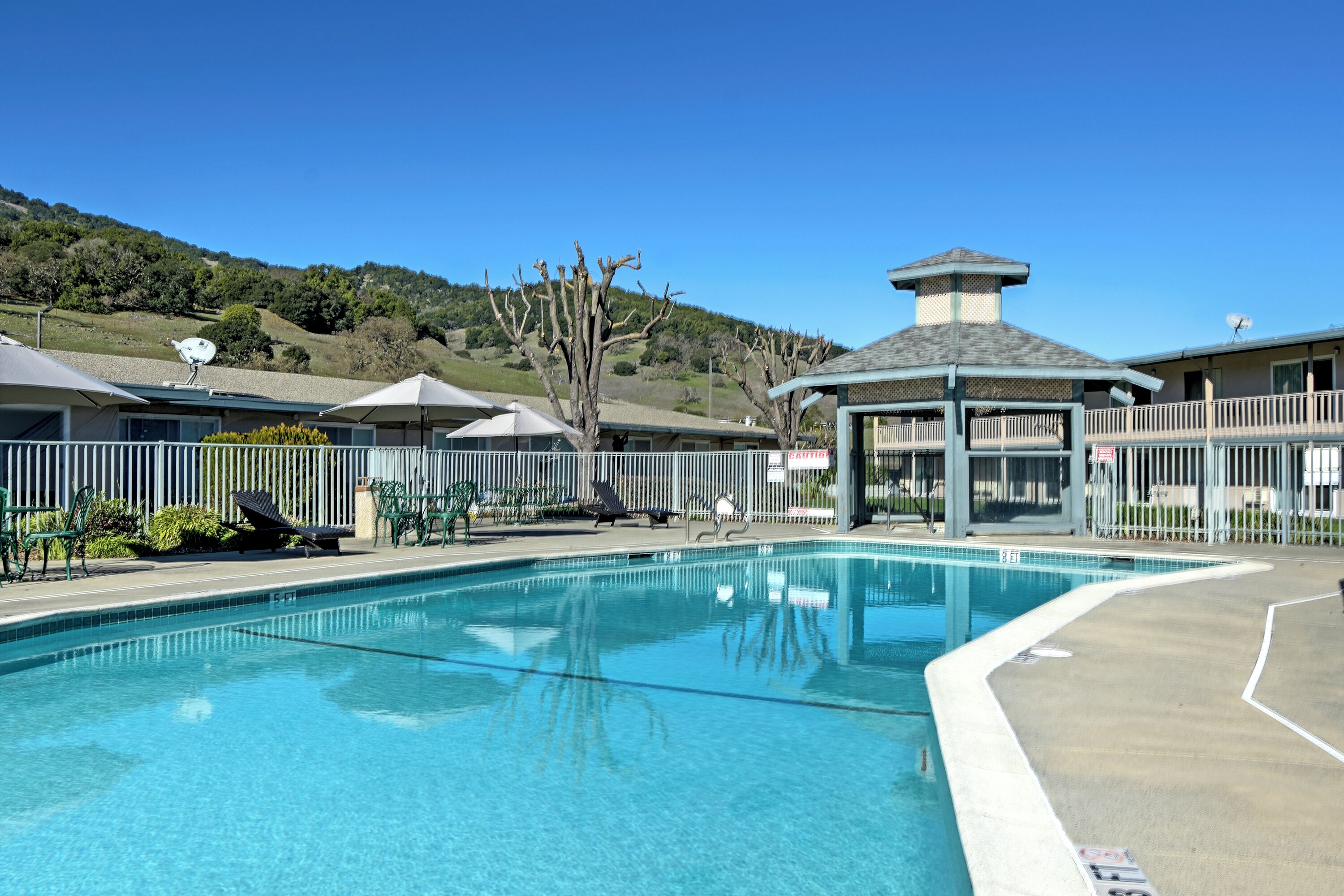 A clear swimming pool with lounge chairs and a gazebo.