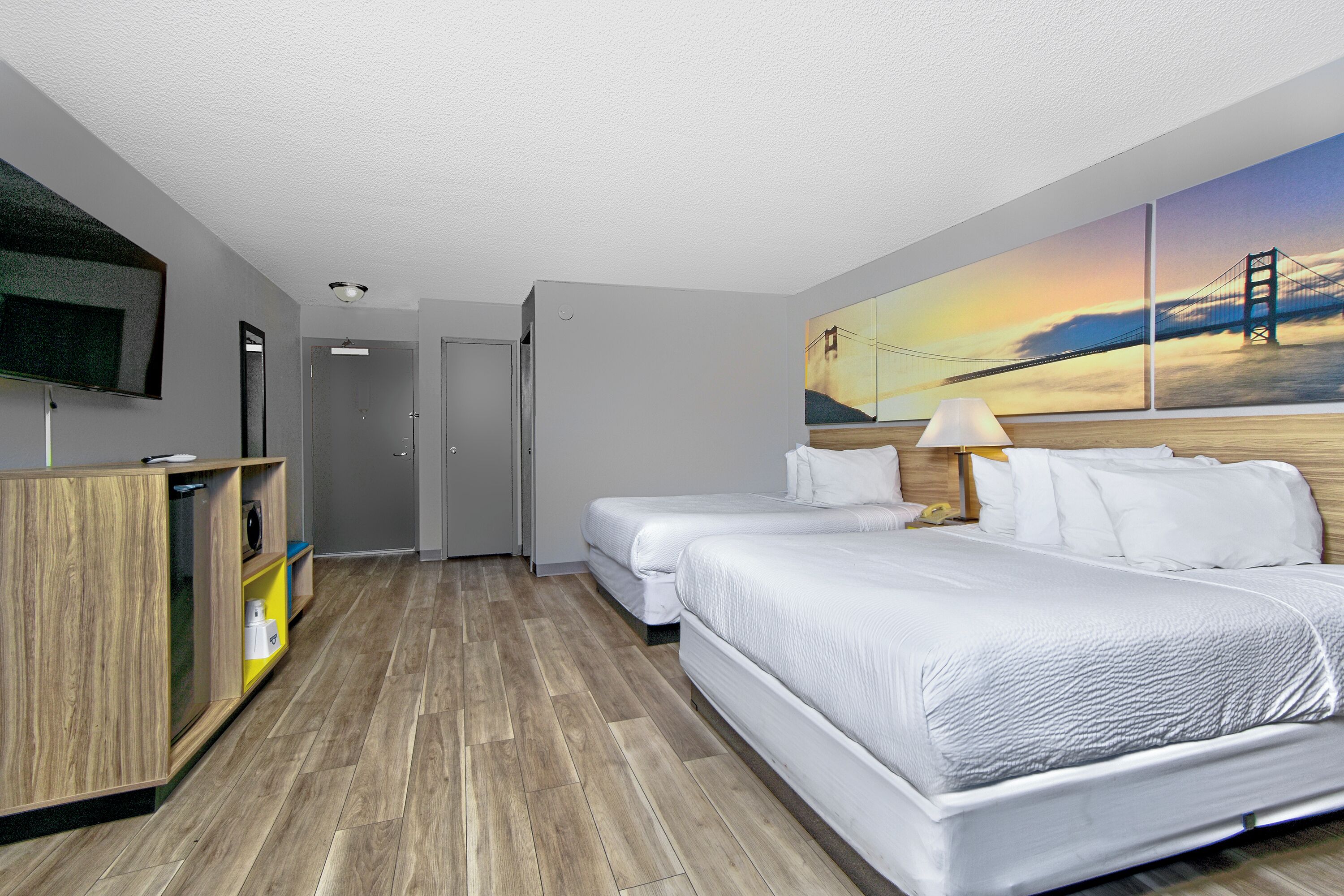 Habitació d'hotel amb dos llits, una televisió, un escriptori i un quadre d'un pont.