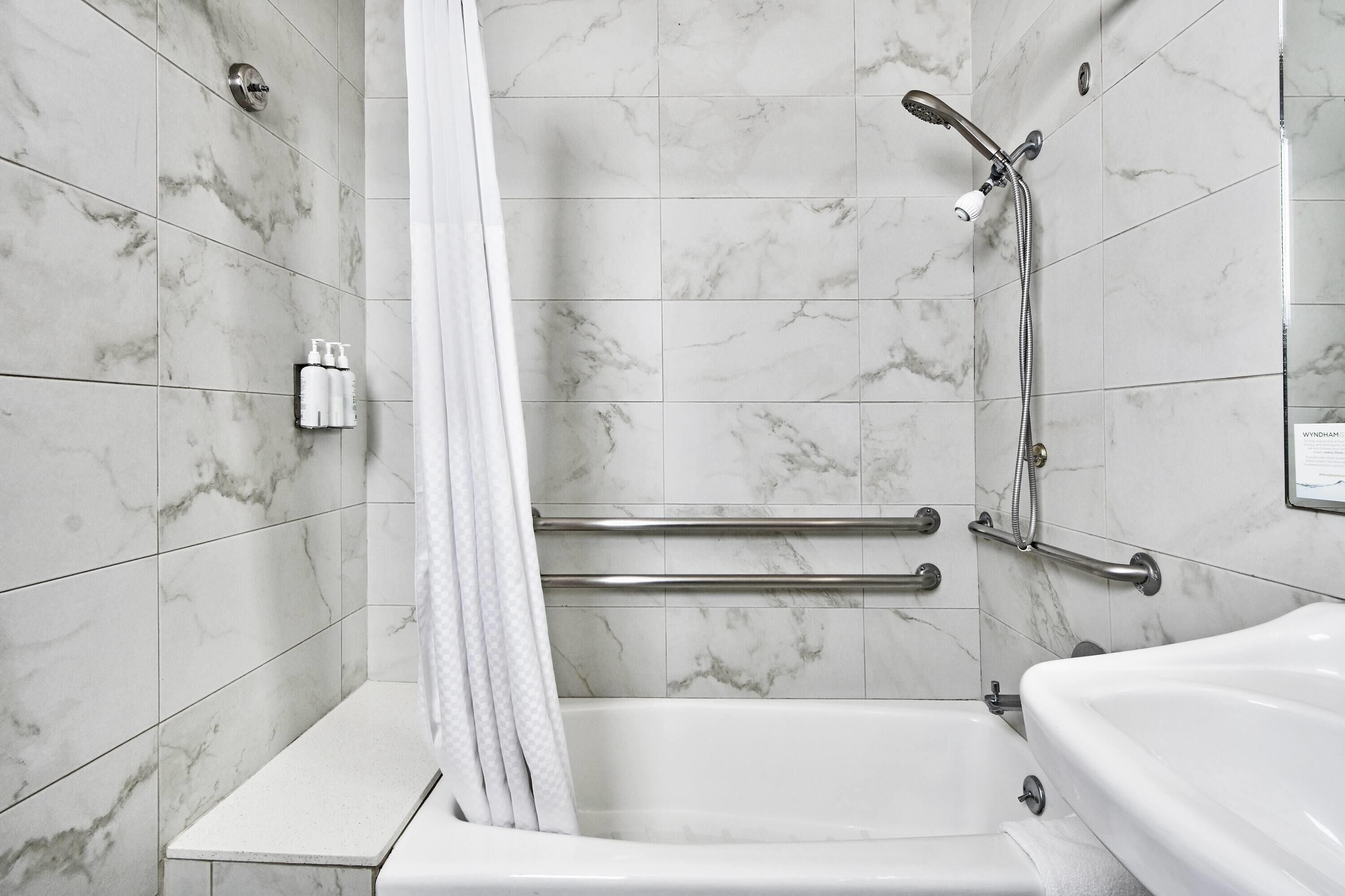 Een badkamer met een bad, een douche en een handgreep.