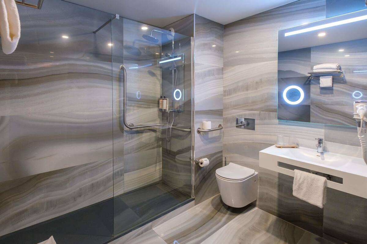 A modern bathroom with a glass-enclosed shower, a white toilet, and a vanity with a mirror.