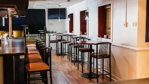 Um restaurante com um balcão comprido, várias mesas e cadeiras.