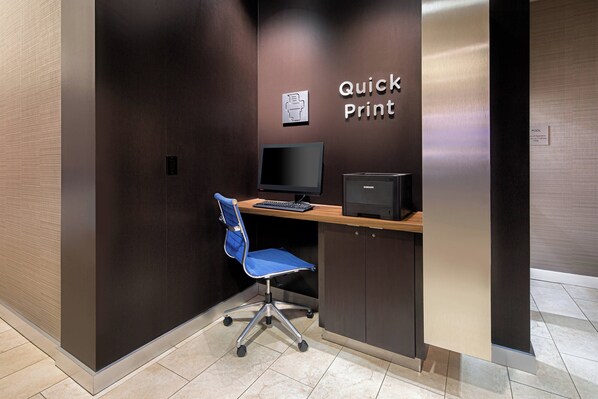 Un pequeño espacio de oficina con un escritorio, una silla, una computadora y un letrero que dice 'Quick Print'.