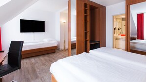 Una habitación de hotel moderna con una cama grande, un escritorio, una silla y un televisor montado en la pared.