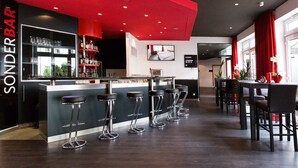 Zona de bar con pared de acento roja, varios taburetes y una barra.