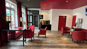 Un lobby moderno con muebles rojos, una chimenea y piso de madera.