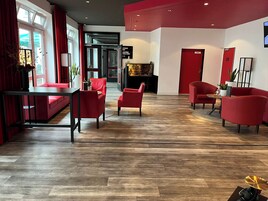 A modern lobby with red furniture, a fireplace, and a wooden floor.