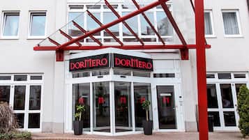 Een hotelingang met een glazen deur en een rode luifel.
