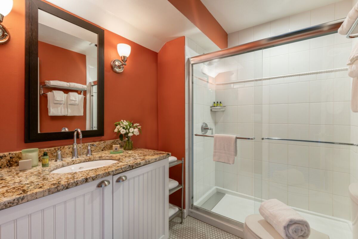 Un baño con tocador doble, un espejo grande, ducha con puerta de vidrio y un perchero para toallas.