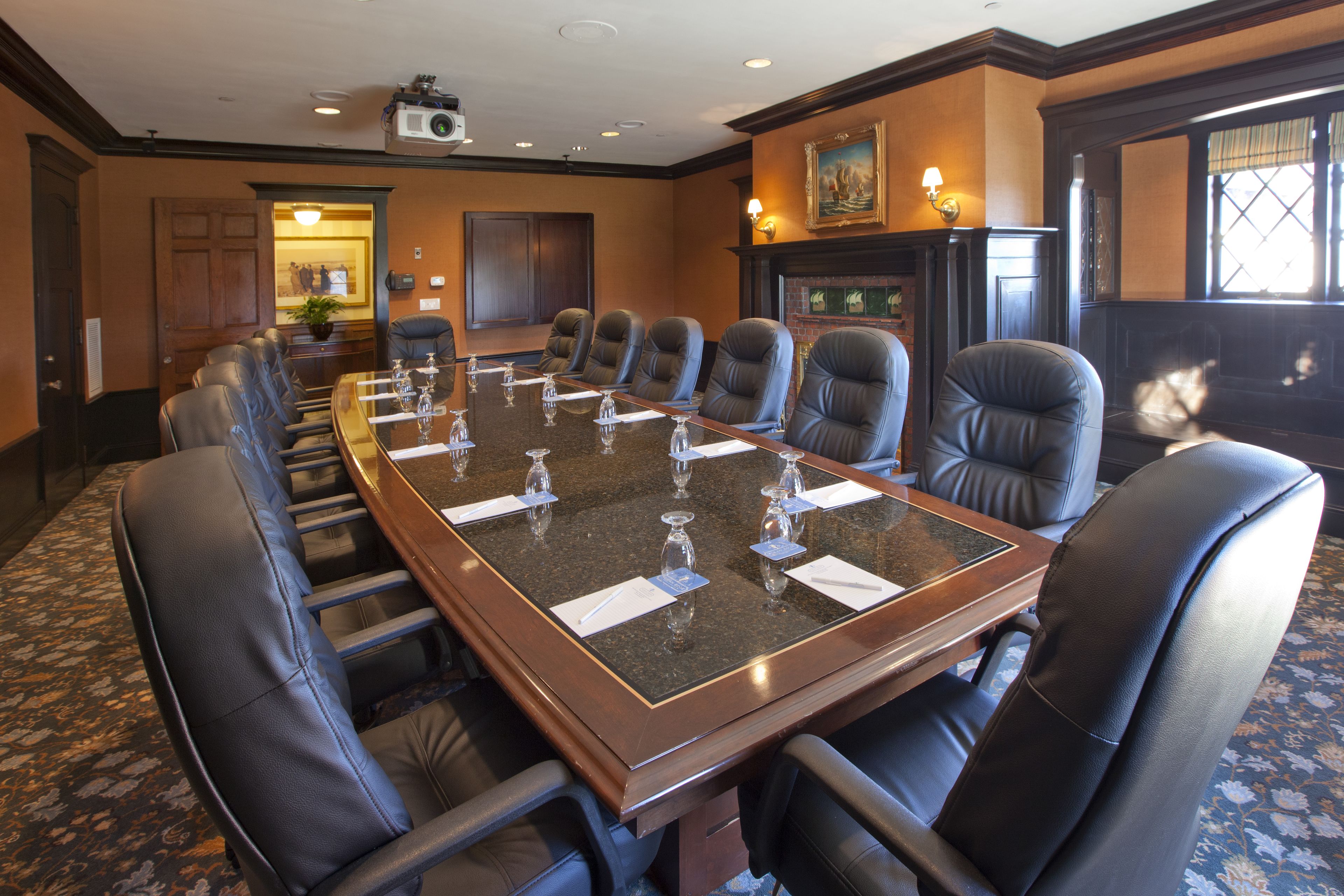 A conference room with a long table, multiple chairs, and a fireplace.