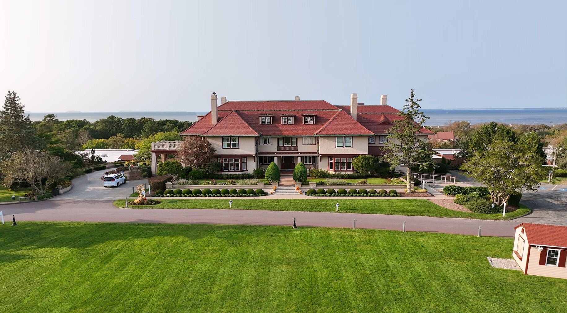A large, two-story house with a red roof, surrounded by a well-maintained lawn and a driveway.