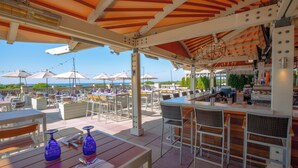 An outdoor patio with tables and chairs, umbrellas, and a bar area. - The Mansion at Ocean Edge (Brewster)