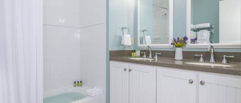 A modern bathroom with a bathtub, a shower, and a vanity with a sink and mirror.