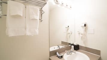 Ein Badezimmer mit Waschbecken, Spiegel, Handtuchhalter und Fön.