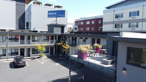 A multi-story hotel with balconies, a parking lot, and a sign for The Grove West Seattle Inn. - The Grove West Seattle Inn (Seattle)