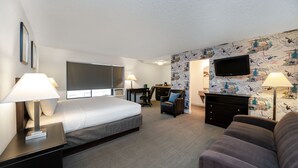 A hotel room with a bed, a desk, a TV, a couch, and a patterned wall. - The Grove West Seattle Inn (Seattle)