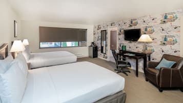 Habitación de hotel con una cama grande, un escritorio con una silla, un televisor y un papel tapiz estampado.