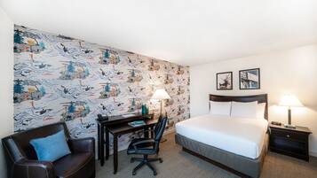Una habitación de hotel con cama, escritorio, silla y dos lámparas de noche.