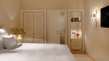 Une chambre à coucher avec un lit, une lampe, un vase de fleurs, une télévision et une armoire.
