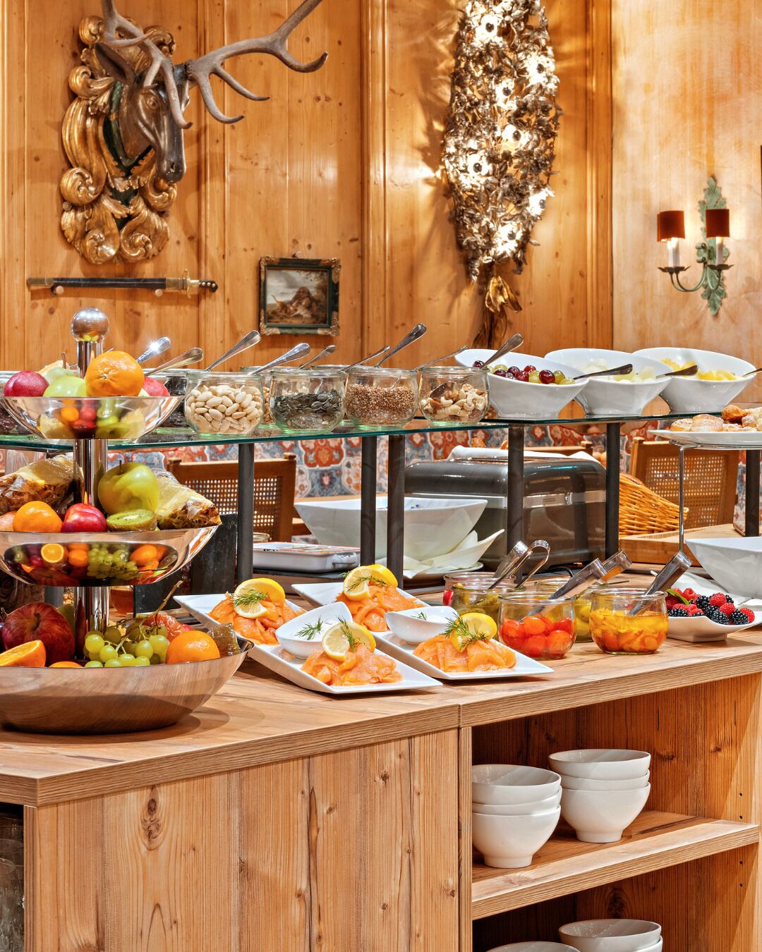 A buffet with various food items and a decorative antler headpiece on the wall.