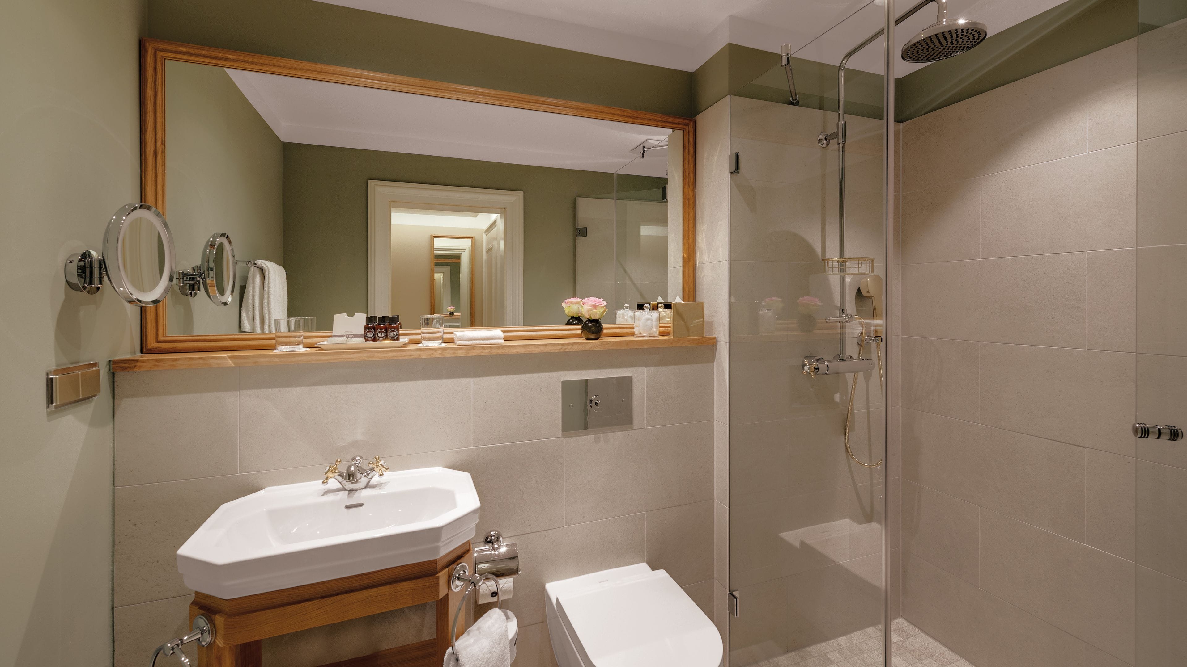 Un baño moderno con un espejo grande, un lavabo, un inodoro y cabina de ducha con mampara de vidrio.
