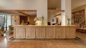 A reception area with a wooden reception desk, a green vase, and a lamp. - Hotel Excelsior München (Munich)