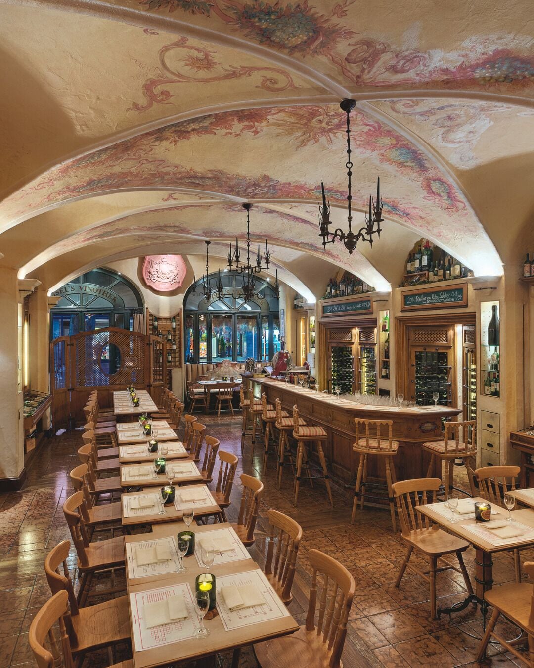 Um restaurante com um amplo espaço de refeições, bar e espaço para exibição de vinhos.