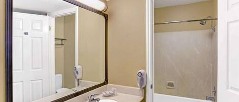 A bathroom with a sink, mirror, and shower.