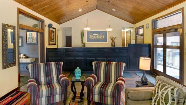 Una habitación acogedora con sillones a rayas, un sofá de color oscuro y un letrero de Baymont.