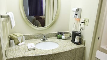 A hotel bathroom with a sink, mirror, towel rack, and toiletries.