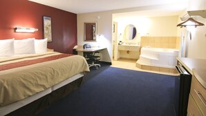 A hotel room with two beds, a desk, a chair, a bathroom with a bathtub, and a mirror. - Red Roof Inn Somerset, KY (Somerset)