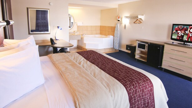 A hotel room with a large bed, a desk with a chair, a television, a bathroom with a bathtub, and a microwave. - Red Roof Inn Somerset, KY (Somerset)