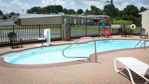 A swimming pool with a brick deck, a lifeguard chair, and a red chair. - Red Roof Inn Somerset, KY (Somerset)