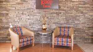 A Red Roof Inn lobby with two armchairs, a small table, and a vase with dried plants. - Red Roof Inn Somerset, KY (Somerset)