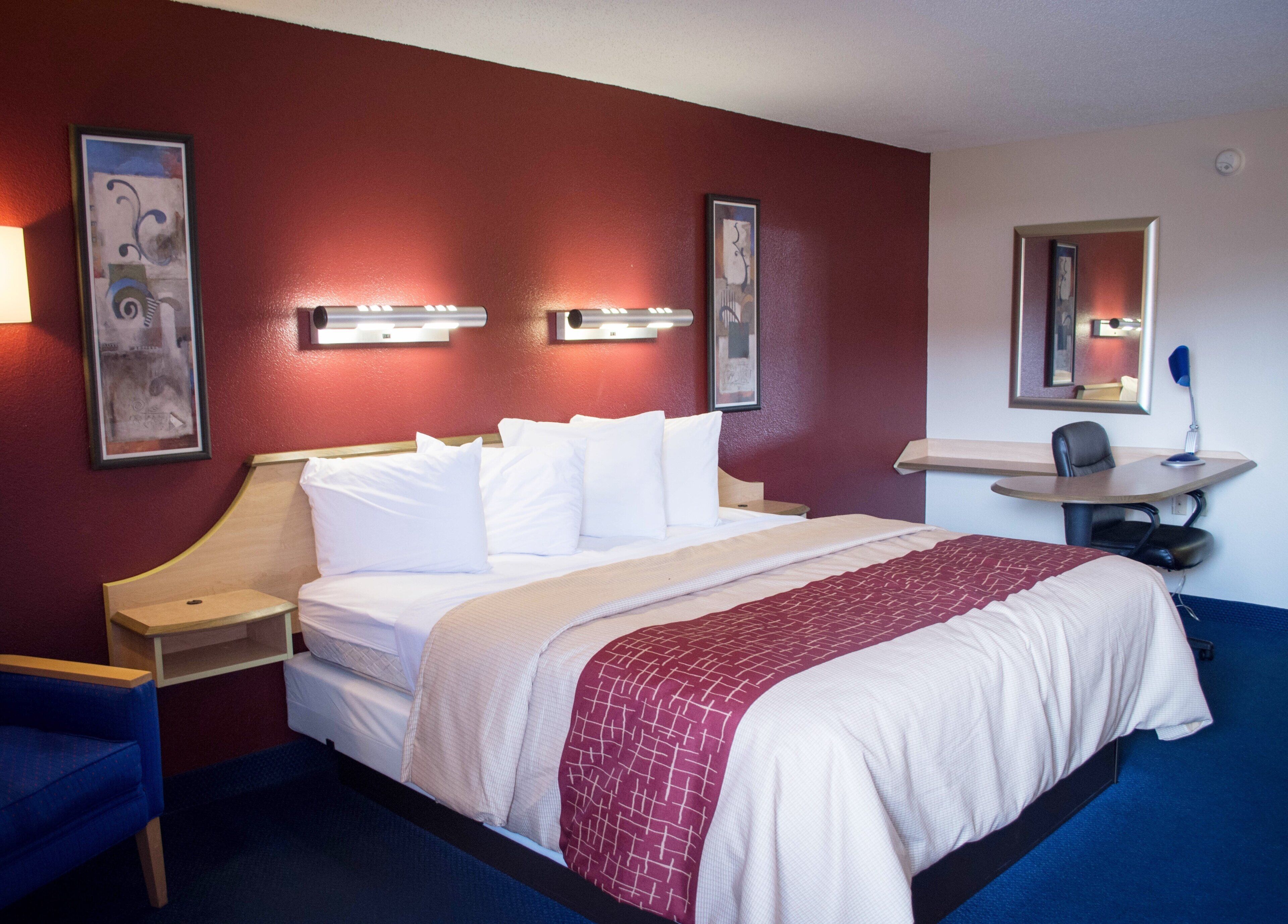 Quarto de hotel com cama, mesas de cabeceira, escrivaninha e uma cadeira.