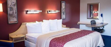 A hotel room with a bed, bedside tables, a desk, and a chair.