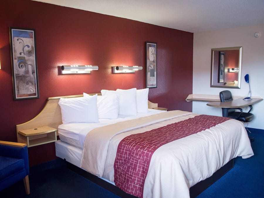 A hotel room with a bed, bedside tables, a desk, and a chair.