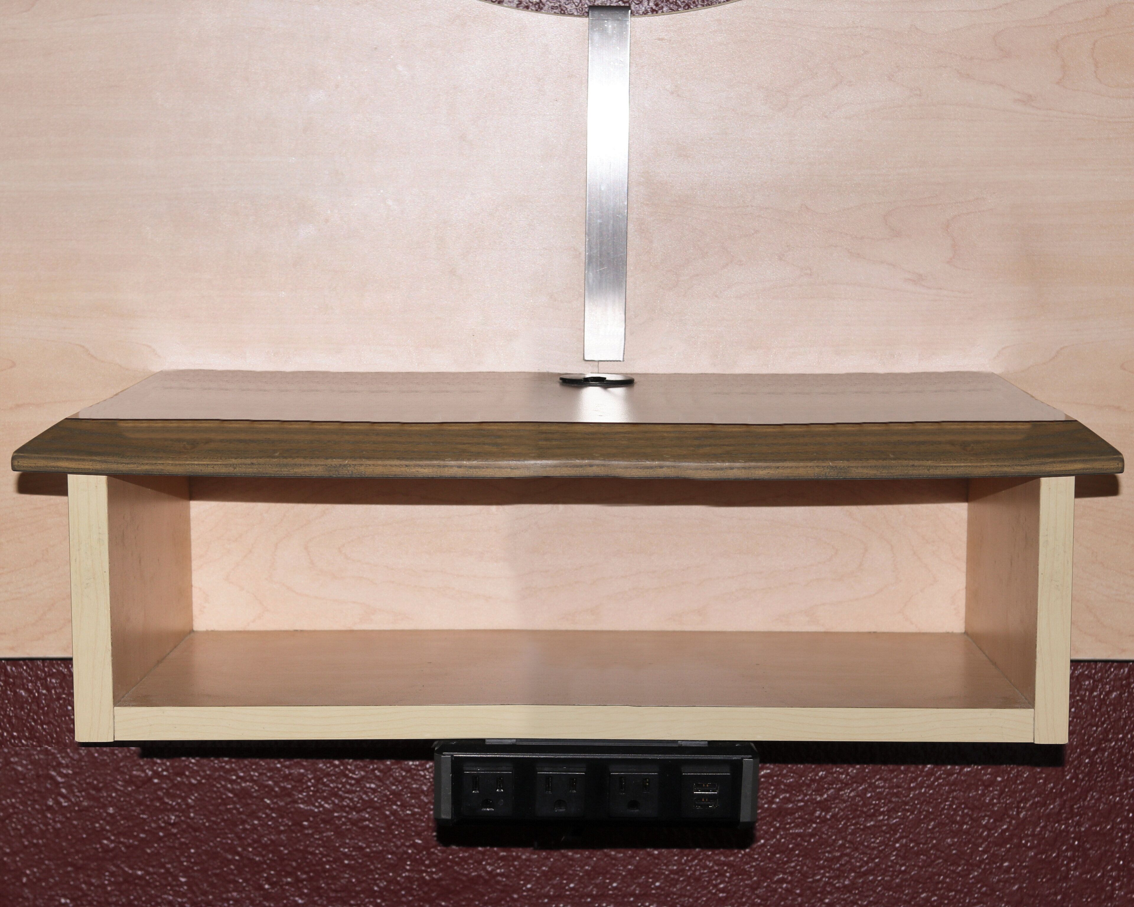 Mesa de madeira com estrutura metálica e uma tomada embaixo.